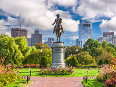 Statue of George Washington on horseback at the entrance of Boston Public Garden with Boston's Financial District in the background.