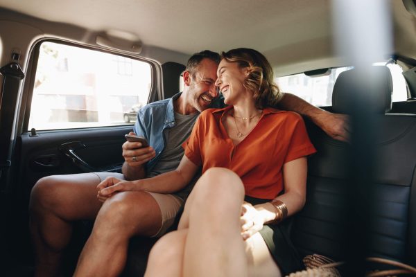 A couple sitting comfortably in the back seat of a luxury car, enjoying a private guided city tour of Boston
